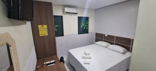 a small bedroom with a bed with white sheets and pillows at Hotel Borari in Alter do Chao