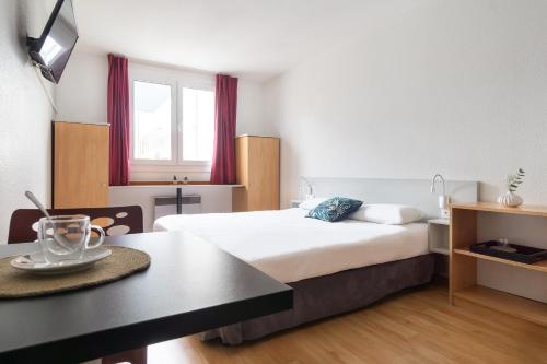 a hotel room with a bed and a table at City Residence Access Strasbourg in Strasbourg