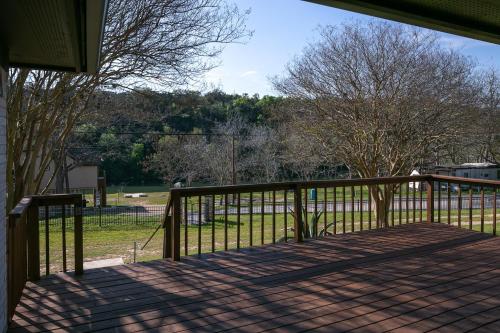 a porch with a fence and trees and a field at Lazy Southern Getaway in Canyon Lake