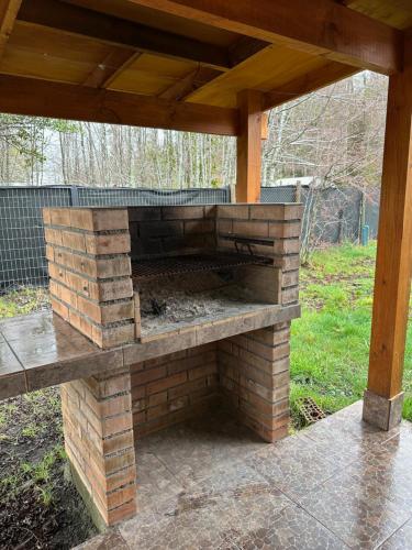 un horno de ladrillo al aire libre con techo de madera en Petruleufu, en Pucón