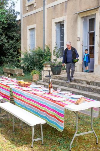 un homme debout devant une table avec une couverture colorée dans l'établissement Château d 'Olonzac - Maison familiale avec grand jardin, à Olonzac