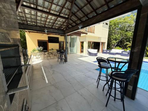 un patio con sedie, tavoli e piscina di Casa de Praia Alto Padrão - Costa do Sauípe, Bahia a Mata de Sao Joao