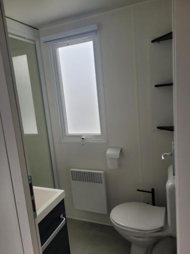 une salle de bain avec toilettes et fenêtre dans l'établissement MH 3 chambres au coeur du camping Bois Dormant 90, à Saint-Jean-de-Monts