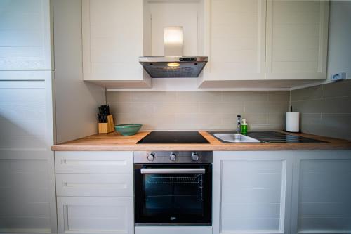 a kitchen with white cabinets and a stove and a sink at Flex SelfCheckIns 169 - Zagreb - Loggia - Parking - 2 Bedroom in Zagreb