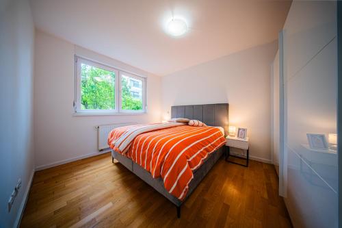 a bedroom with a bed with an orange comforter and a window at Flex SelfCheckIns 169 - Zagreb - Loggia - Parking - 2 Bedroom in Zagreb