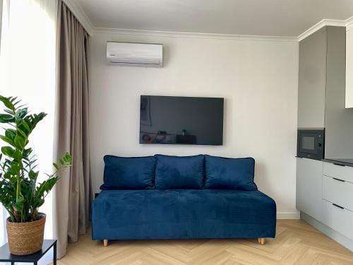 a blue couch in a living room with a tv at Nexiti Apartments - Centrum - Metro - Palace of Culture - Philharmonic in Warsaw