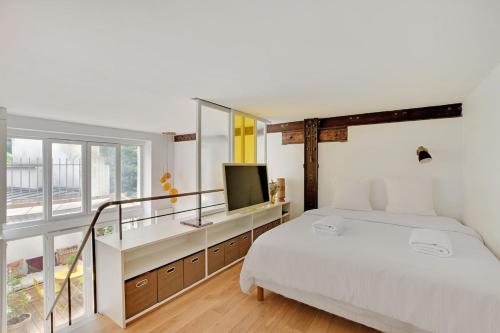 une chambre blanche avec un lit et une télévision dans l'établissement Bright loft with terrace - Belleville, à Paris