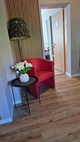 a red couch and a table with a vase of flowers at Pension STELLA in Lutherstadt Eisleben