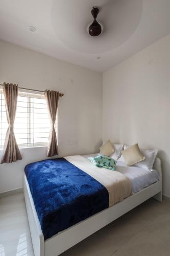 a bedroom with a large bed with a blue blanket at Whispering Willows By Red Olive 3BHK Near Airport in Yelahanka