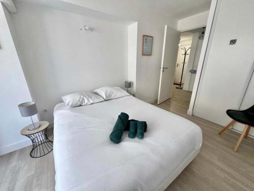 un lit blanc avec deux nœuds papillon verts dessus dans l'établissement Agde-Loc Appartement des Flaneries, au Cap d'Agde