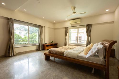 コルカタにあるVictoria Apartment by JadeCaps Chowringheeのベッドと2つの窓がある寝室
