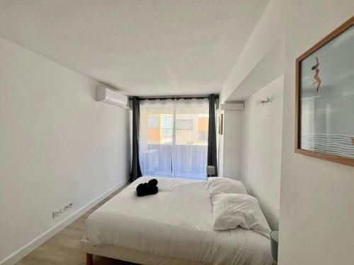 - un chat noir assis sur un lit dans une chambre dans l'établissement Agde-Loc Appartement des Flaneries, au Cap d'Agde