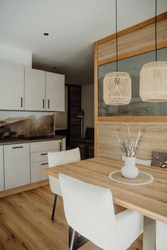 una cucina con un tavolo in legno e mobili bianchi di SAM`s hairBERGE Apartments a Lofer