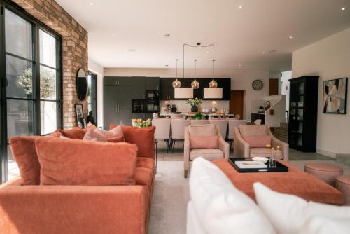 a living room with orange furniture and a kitchen at Verdant Rise - Contemporary Country Retreat in Albourne