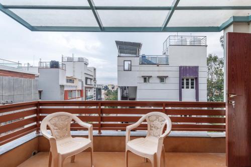 two chairs on a balcony with buildings in the background at Terrastone Duplex Spacious ApartmentNr Lake in Bengaluru