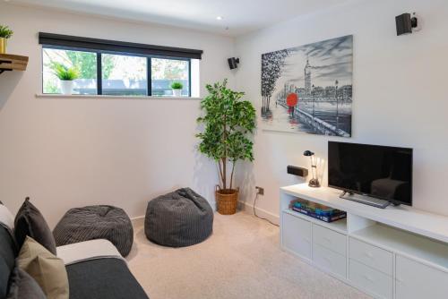 a living room with a couch and a flat screen tv at Verdant Rise - Contemporary Country Retreat in Albourne