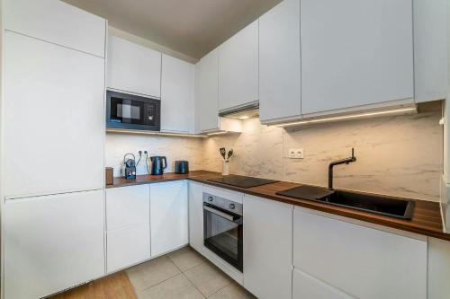 a white kitchen with white cabinets and a sink at Hakuna Matata Lodge - Disney à 5 min in Serris