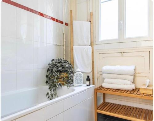 La salle de bains est pourvue d'une baignoire et d'une étagère avec des serviettes. dans l'établissement Maison à Paris, à La Celle-sous-Gouzon