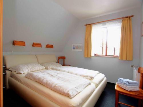 a bedroom with a bed with white sheets and a window at Gaestehaus-Bruhn-3 in Alkersum
