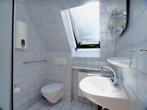 a bathroom with a toilet and a sink and a window at Gaestehaus-Bruhn-3 in Alkersum