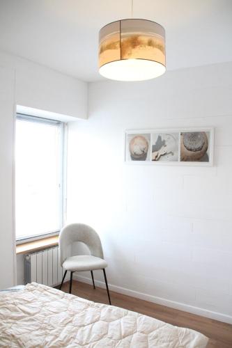 une chambre avec un lit, une chaise et une fenêtre dans l'établissement L'Amiral - vue mer sur le port, à Roscoff