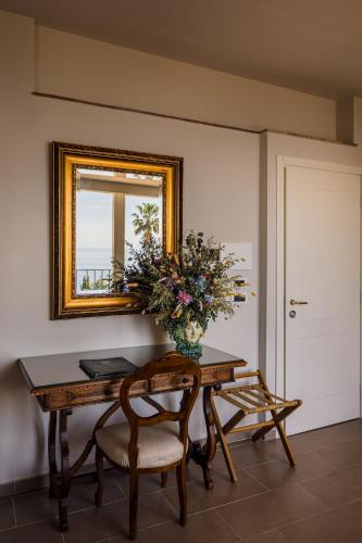 a table with a vase of flowers and a mirror at Hotel Villa Paradiso in Taormina