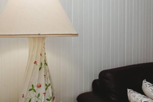 a lamp with a white lamp shade next to a couch at Forest Cottage. Great Location, Free WiFi in Methven