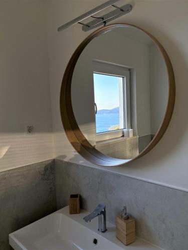 a bathroom mirror with a sink and a window at Tina's Sunset Haven in Ustrine