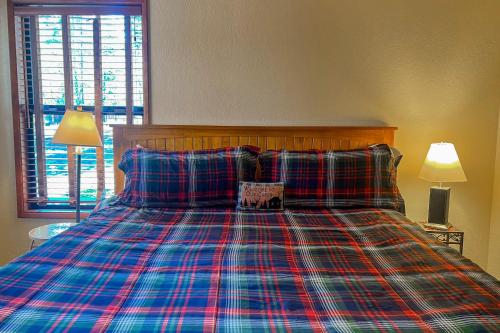 a bed with a plaid blanket and two pillows at Otter Lane 12 | Discover Sunriver in Sunriver