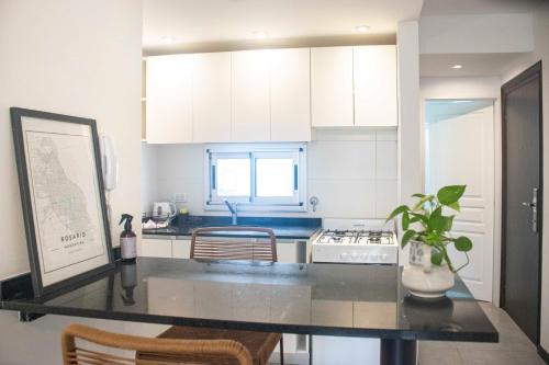 Una cocina con gabinetes blancos y una encimera negra. en Dorrego House, en Rosario