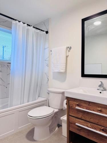 a white bathroom with a toilet and a sink at Charming Queen Bedroom with Bathroom Vancouver West in Vancouver