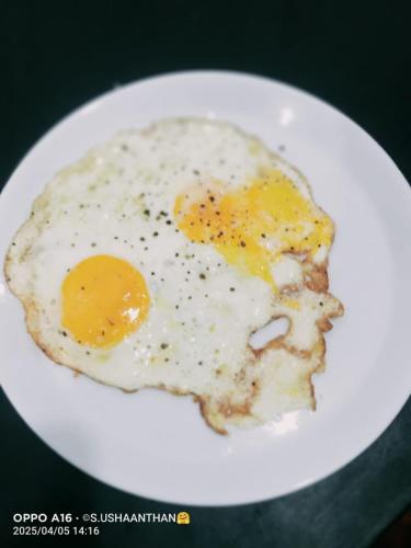 a fried egg on a white plate on a table at Trinco Chill Zone Hostel in Trincomalee