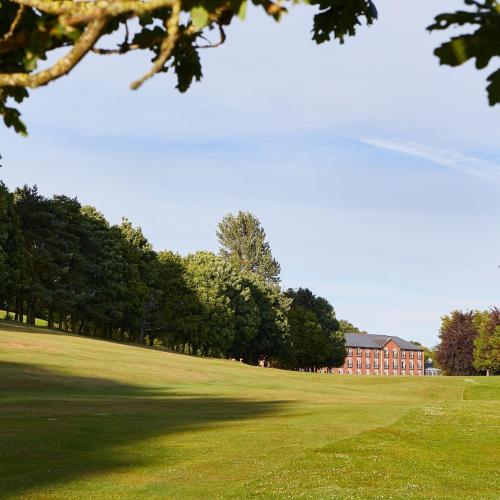 a green field with a building in the background at Macdonald Hill Valley Hotel, Spa & Golf Resort in Whitchurch
