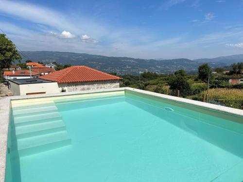 a blue swimming pool with a view of a house at Casa Laurinha by Lethes Legacy in Ponte de Lima
