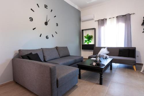 a living room with a couch and a clock on the wall at Etheria Apartment in Artemida
