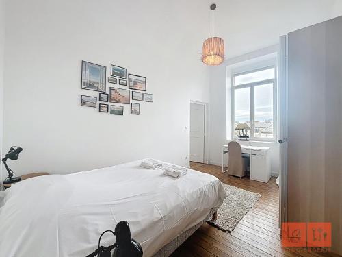 een slaapkamer met een bed, een bureau en een raam bij La parenthèse in Wimereux