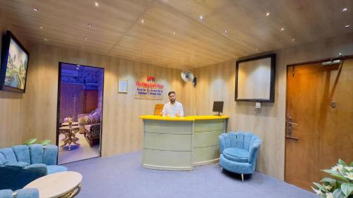 a man standing at a counter in a room with chairs at City Palace Guest House in Dhaka