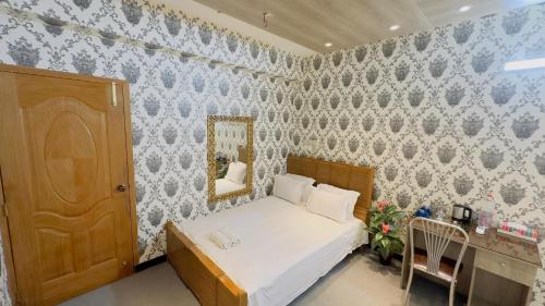 a small bedroom with a bed and a mirror at City Palace Guest House in Dhaka