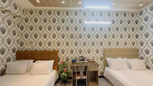 a bedroom with two beds and a wall with wallpaper at City Palace Guest House in Dhaka