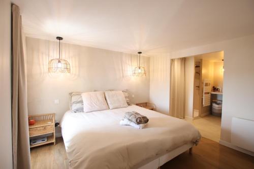 a bedroom with a large white bed with two lights at Maison Bello - La Suite Bohème in Beaupréau