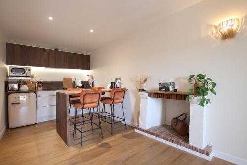 une cuisine avec un bar avec deux tabourets et une cheminée dans l'établissement Maison Bello - La Suite Bohème, à Beaupréau