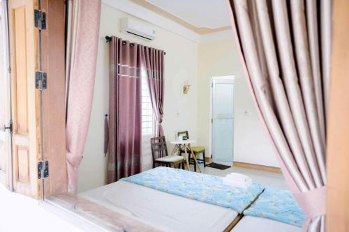 a bedroom with a bed and a chair and a window at Nhà nghỉ Biển Xanh in Hộ Vệ