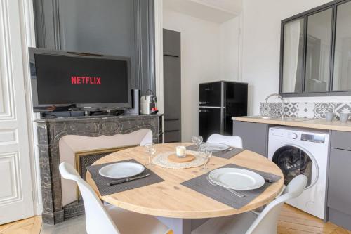 une salle à manger avec une table et une télévision dans l'établissement Charme et Caractère 10 min Bellecour, à Lyon