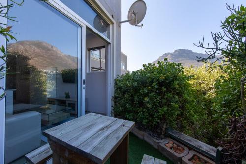 a patio with a wooden bench and a window at The beachclub 17 in Hout Bay