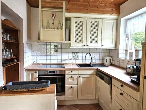 a kitchen with white cabinets and a stove top oven at Haus Klinsterwald in Sankt Oswald