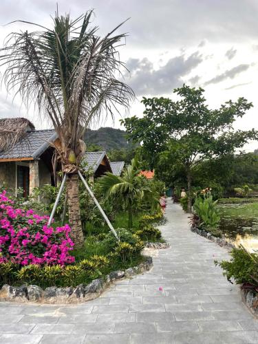 a garden with a palm tree and pink flowers at Hang Mua Luxury Homestay in Xuân Sơn