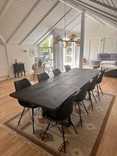 a black dining table and chairs in a living room at Cozy holiday home - spa, hot tub and play room - close to Marielyst square in Bøtø By