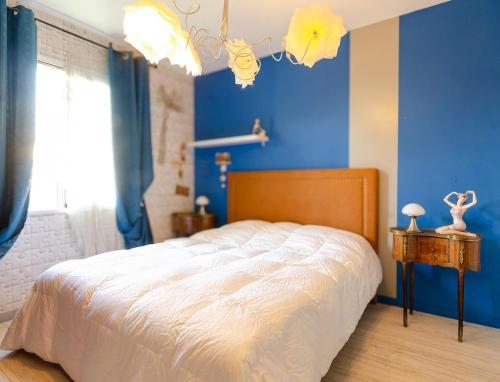 ein Schlafzimmer mit einem Bett mit einer blauen Wand in der Unterkunft Villa neuve tout confort SHABBY CHIC in Talmont