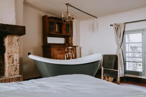 a bathroom with a green bath tub next to a bed at Unique historical home, middle of the village, bath & patio in Tourtour
