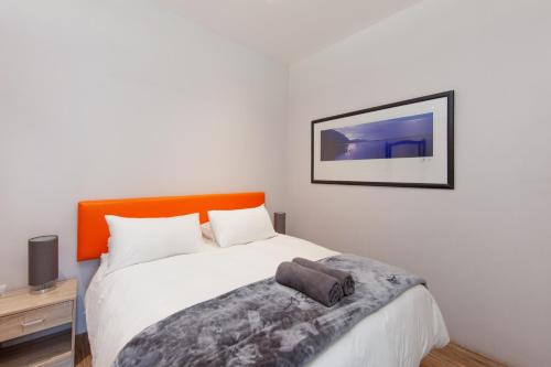 a bedroom with a white bed with an orange headboard at The beachclub 17 in Hout Bay